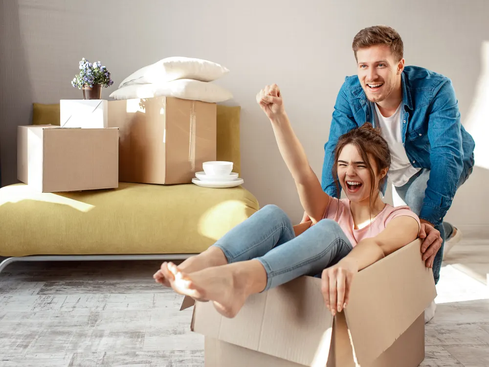 Un couple qui s’amuse dans un carton de déménagement, dans son nouveau logement